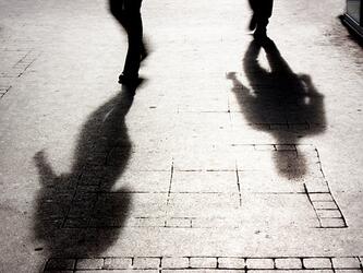 dark shadows of people walking on street